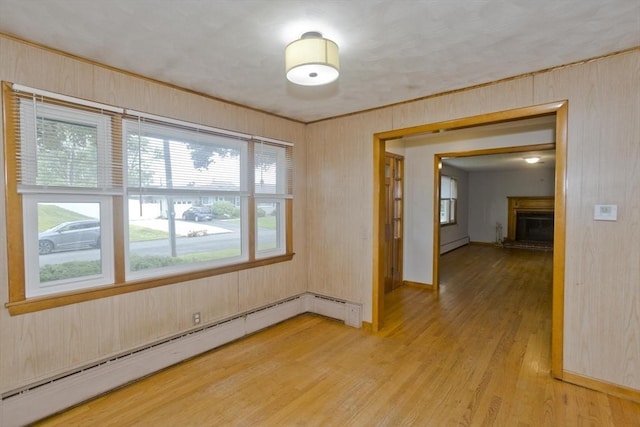 13 Louise Ave, Chicopee, MA 01013 - unfurnished room featuring a baseboard radiator, light wood-style flooring, a fireplace with raised hearth, and wooden walls