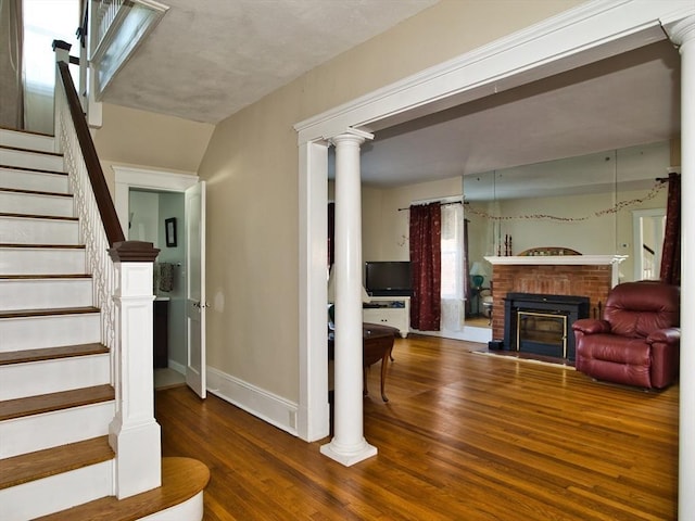 staircase featuring hardwood / wood-style flooring and a brick fireplace