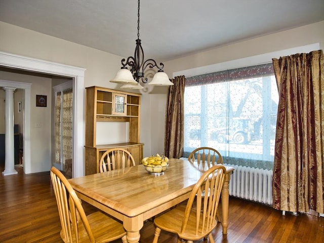 dining space featuring a notable chandelier, dark hardwood / wood-style floors, and ornate columns