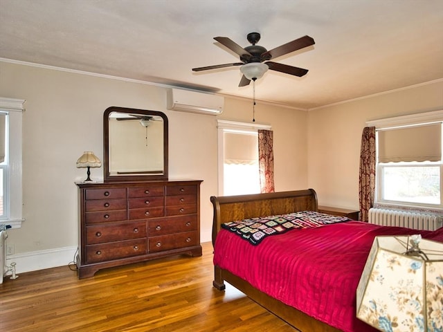 bedroom with a wall mounted air conditioner, radiator, crown molding, hardwood / wood-style flooring, and ceiling fan