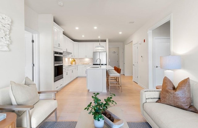 living room featuring sink and light hardwood / wood-style flooring