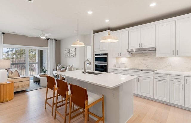 kitchen featuring white cabinetry, sink, ceiling fan, decorative light fixtures, and light wood-type flooring