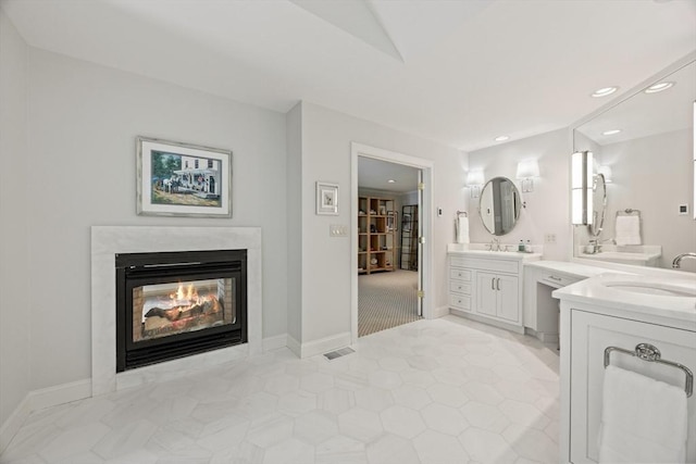 bathroom featuring a multi sided fireplace and vanity