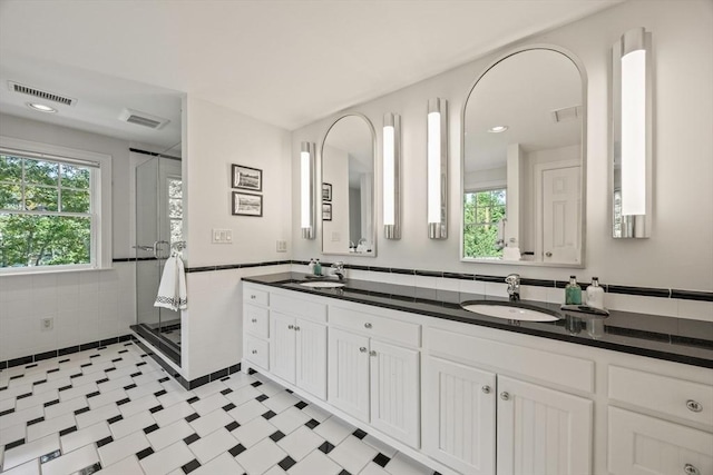 bathroom with vanity, a shower with door, and tile walls