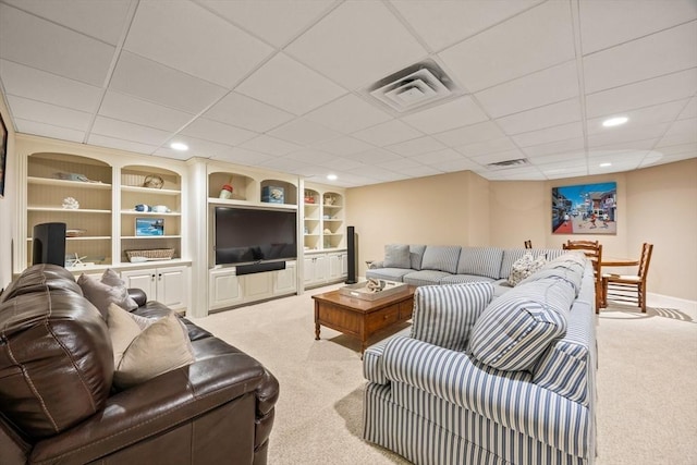 living room with a paneled ceiling, built in shelves, and light carpet