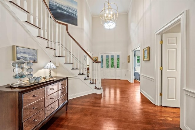 foyer entrance with dark hardwood / wood-style flooring, crown molding, a high ceiling, and a chandelier