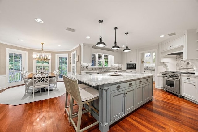 kitchen featuring gray cabinetry, hanging light fixtures, tasteful backsplash, dark hardwood / wood-style floors, and high end stove