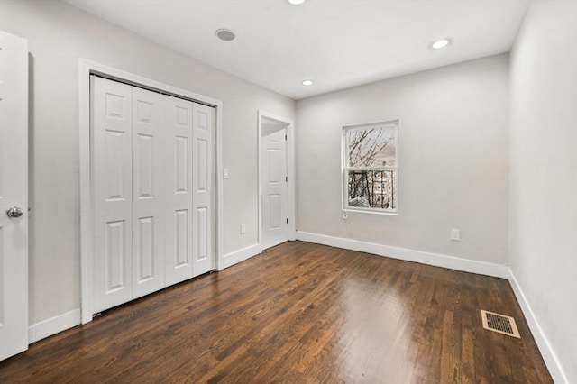 unfurnished bedroom featuring a closet and dark hardwood / wood-style flooring