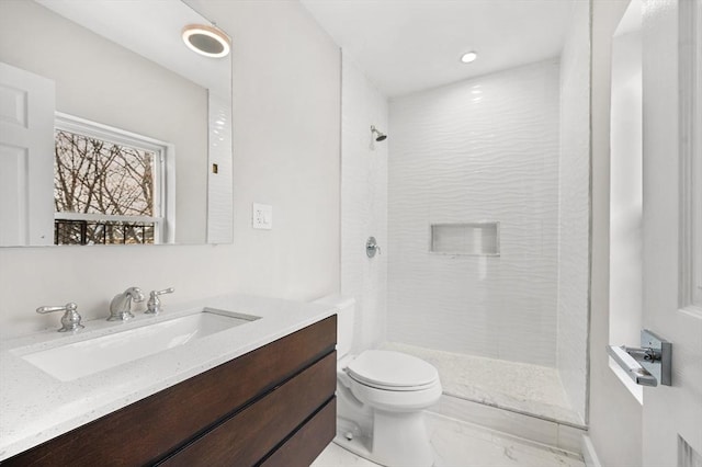 bathroom with vanity, toilet, and a tile shower