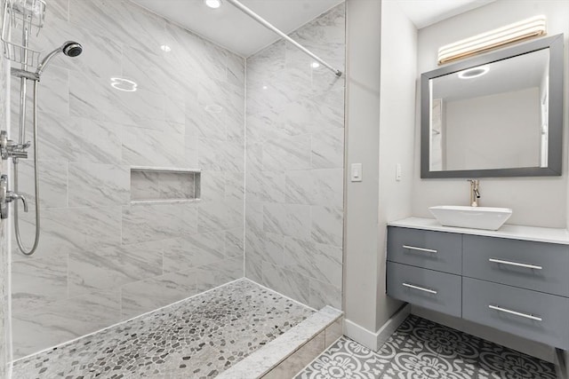 bathroom featuring tiled shower, vanity, and tile patterned flooring