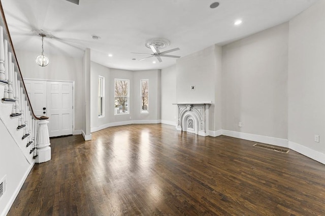 unfurnished living room featuring ceiling fan with notable chandelier and dark hardwood / wood-style flooring