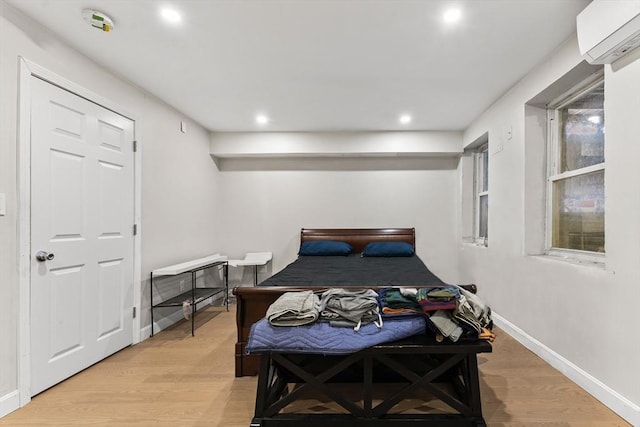 bedroom with a wall mounted air conditioner and light hardwood / wood-style flooring