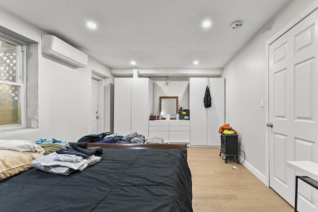 bedroom featuring a wall unit AC and light wood-type flooring