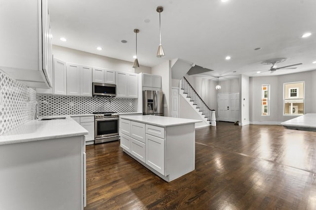 kitchen featuring white cabinetry, stainless steel appliances, a kitchen island, and hanging light fixtures