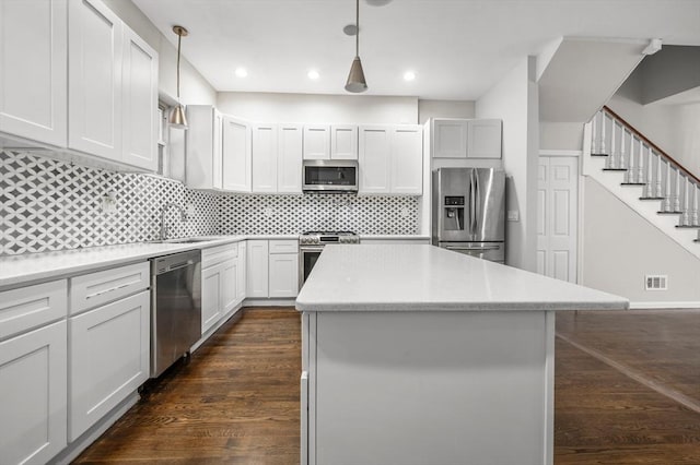 kitchen featuring white cabinets, a center island, dark hardwood / wood-style flooring, stainless steel appliances, and hanging light fixtures