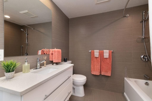 bathroom featuring vanity, shower / bathtub combination, toilet, and tile walls