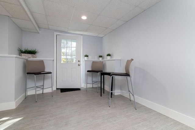 interior space featuring baseboards, a drop ceiling, and wood finished floors