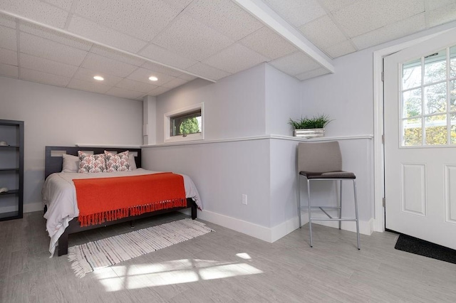 bedroom featuring baseboards, a drop ceiling, and wood finished floors