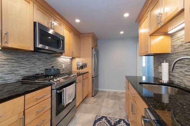 kitchen featuring a sink, dark stone countertops, stainless steel appliances, baseboards, and tasteful backsplash