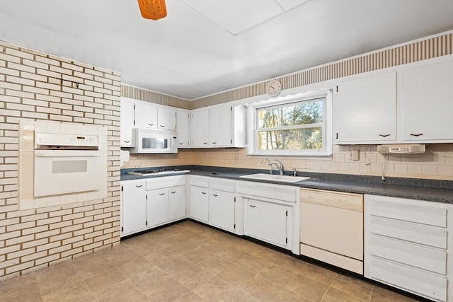 kitchen with sink, white cabinets, white appliances, ceiling fan, and brick wall