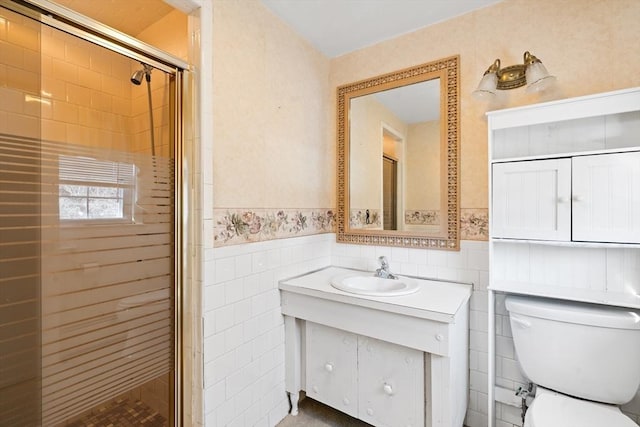 bathroom with toilet, a shower with shower door, tile walls, and vanity