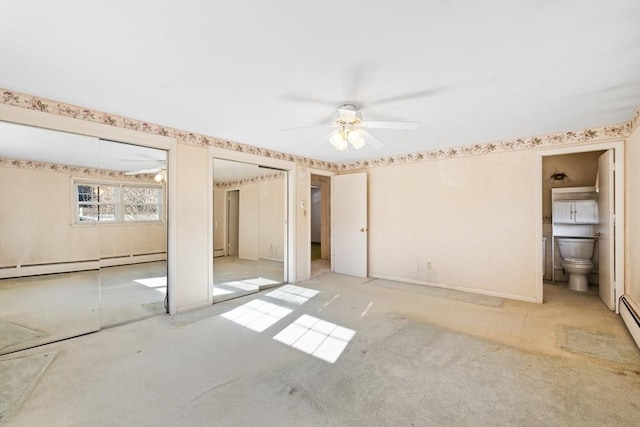 unfurnished bedroom with ensuite bath, light colored carpet, ceiling fan, multiple closets, and a baseboard heating unit