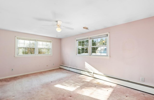 carpeted empty room featuring ceiling fan, a wealth of natural light, and a baseboard heating unit