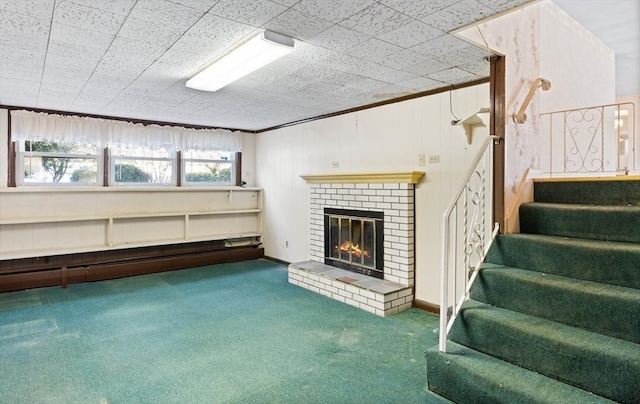 basement with a brick fireplace, carpet floors, and crown molding