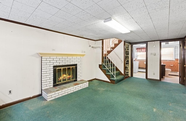 unfurnished living room featuring a baseboard heating unit, a brick fireplace, carpet floors, and ornamental molding