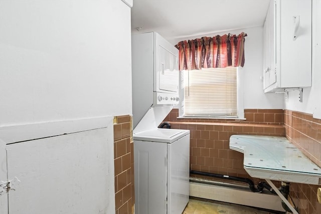 laundry room with tile walls and stacked washer and dryer