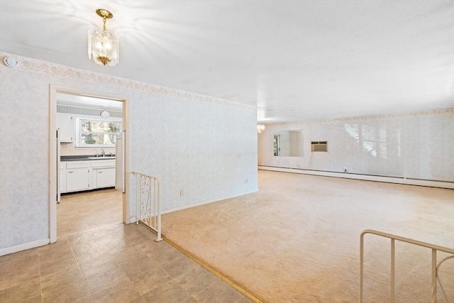 spare room featuring a baseboard heating unit, light colored carpet, a notable chandelier, and sink