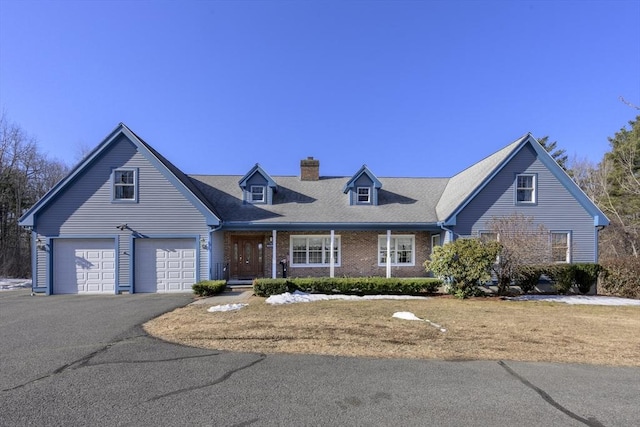 cape cod home with a garage, brick siding, driveway, and a chimney