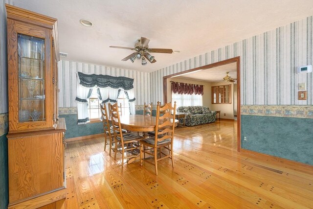 dining room with wallpapered walls, light wood-style floors, and ceiling fan