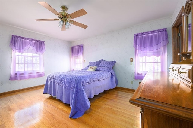 bedroom featuring light wood-type flooring, multiple windows, and wallpapered walls