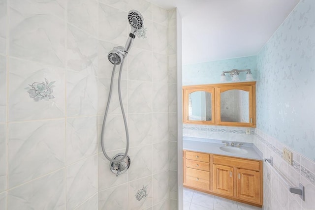 full bath with vanity, tile walls, a tile shower, and wallpapered walls