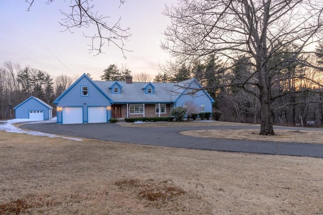 view of front of home featuring aphalt driveway, an attached garage, and a chimney