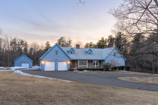view of front facade with aphalt driveway, a garage, a chimney, and a front yard
