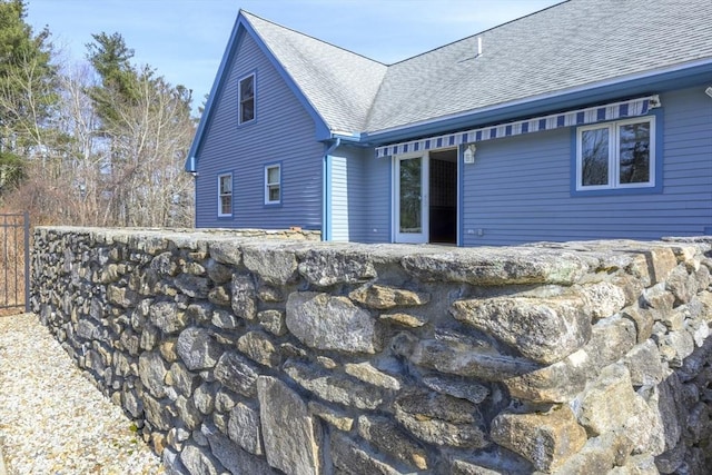 back of house featuring fence and roof with shingles