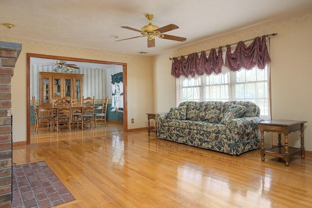 living room featuring visible vents, baseboards, a ceiling fan, and wood finished floors
