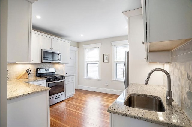 8 Cambridge Ter Unit 2, Cambridge, MA 02140 - kitchen with appliances with stainless steel finishes, a sink, backsplash, light stone countertops, and light wood finished floors