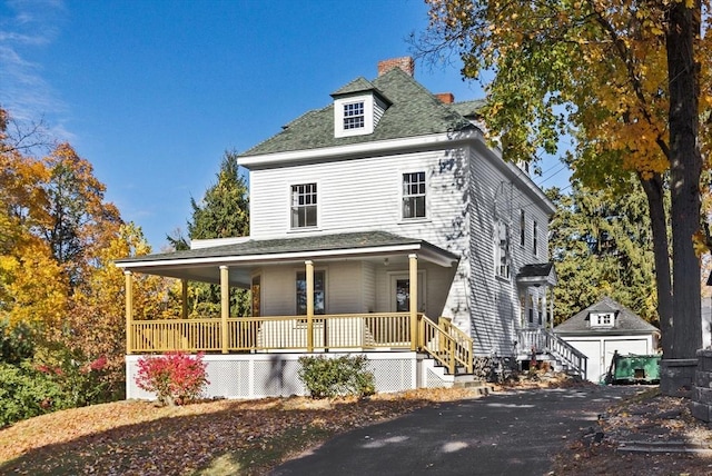 view of front of home featuring a porch, a garage, an outdoor structure, a shed, and a chimney