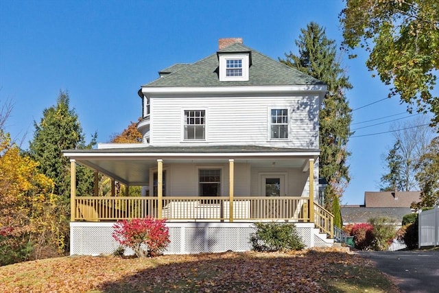 view of front of house featuring a shingled roof, a chimney, and a porch