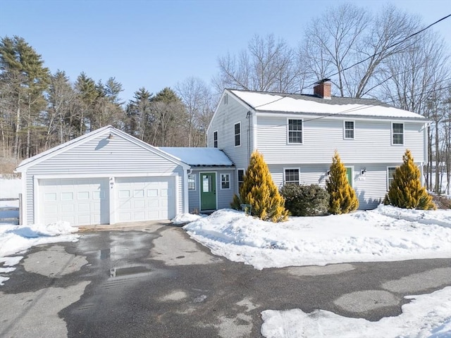 colonial house with a garage, a chimney, and aphalt driveway