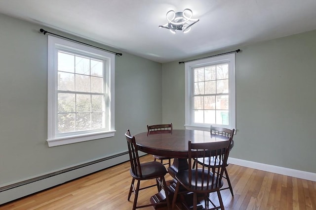 dining area featuring baseboards, a baseboard radiator, and light wood-style floors