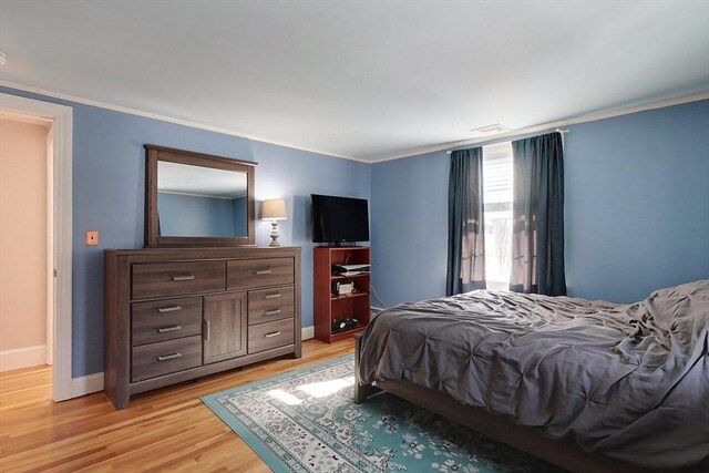 bedroom featuring light wood-type flooring, baseboards, and crown molding