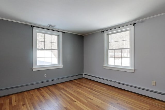 spare room with a baseboard heating unit, ornamental molding, light wood-style flooring, and a healthy amount of sunlight