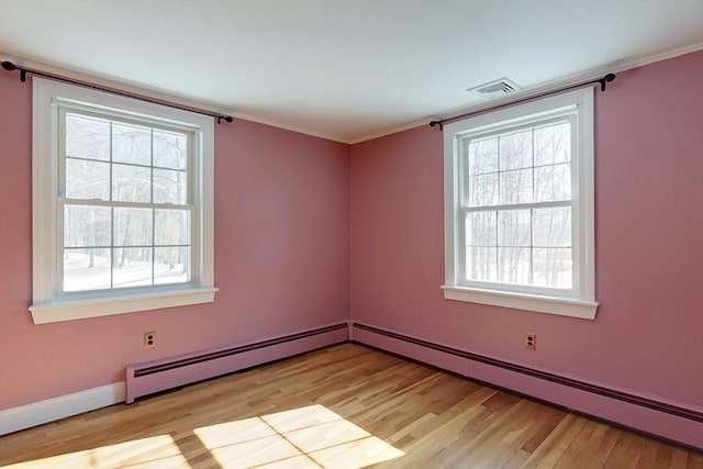 spare room featuring light wood-type flooring, plenty of natural light, visible vents, and baseboard heating