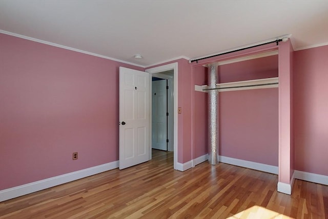 unfurnished bedroom featuring baseboards, ornamental molding, a closet, and light wood-style floors