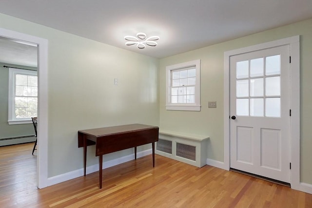 doorway featuring light wood-style floors, baseboard heating, and baseboards