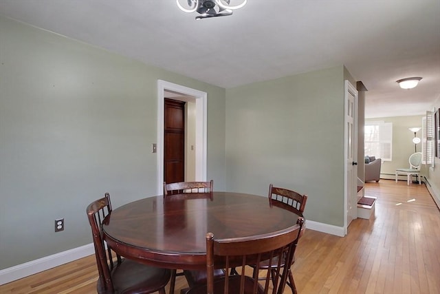 dining space featuring a baseboard radiator, light wood-style flooring, and baseboards